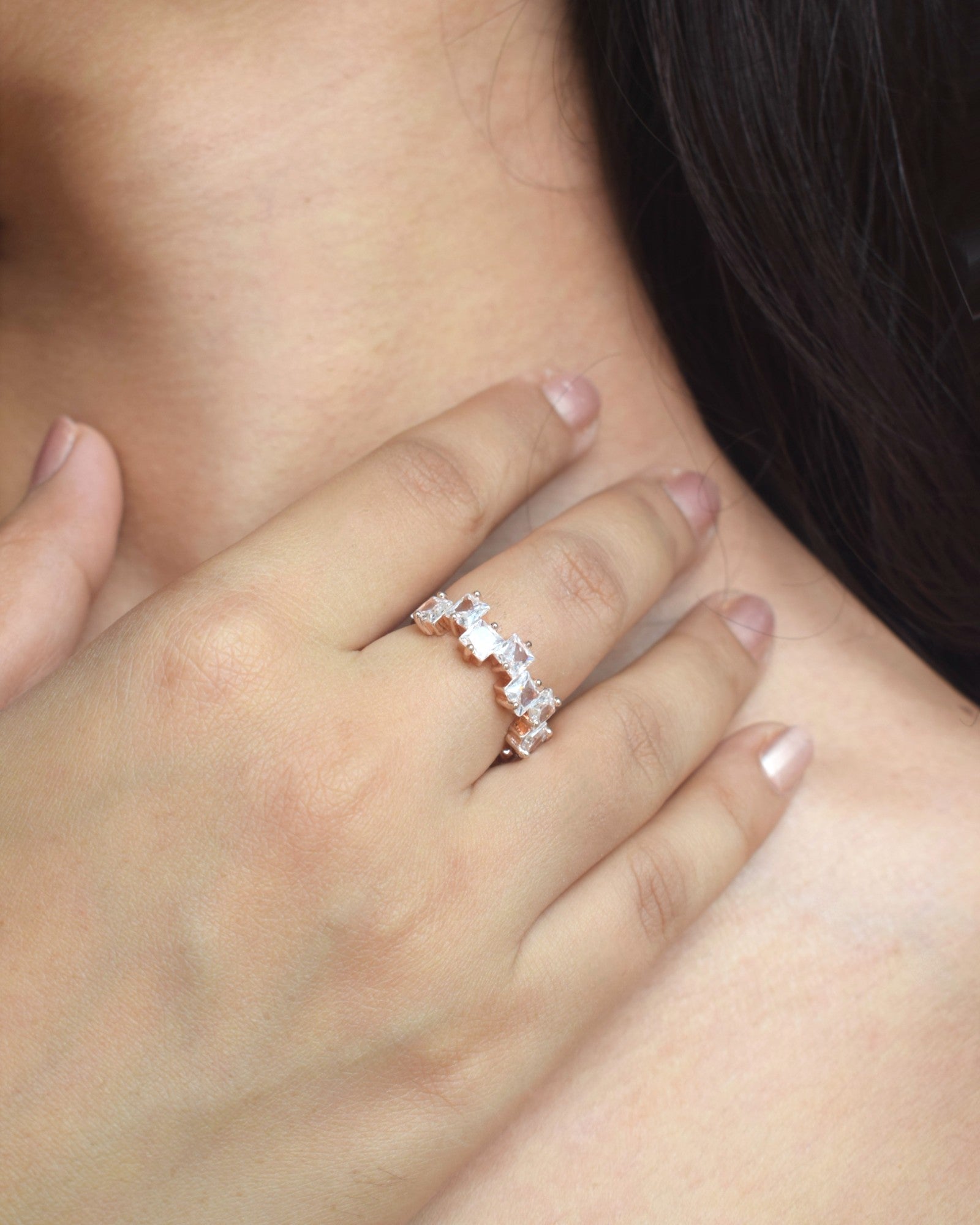 Close-up of a hand wearing a diamond ring on a neutral background