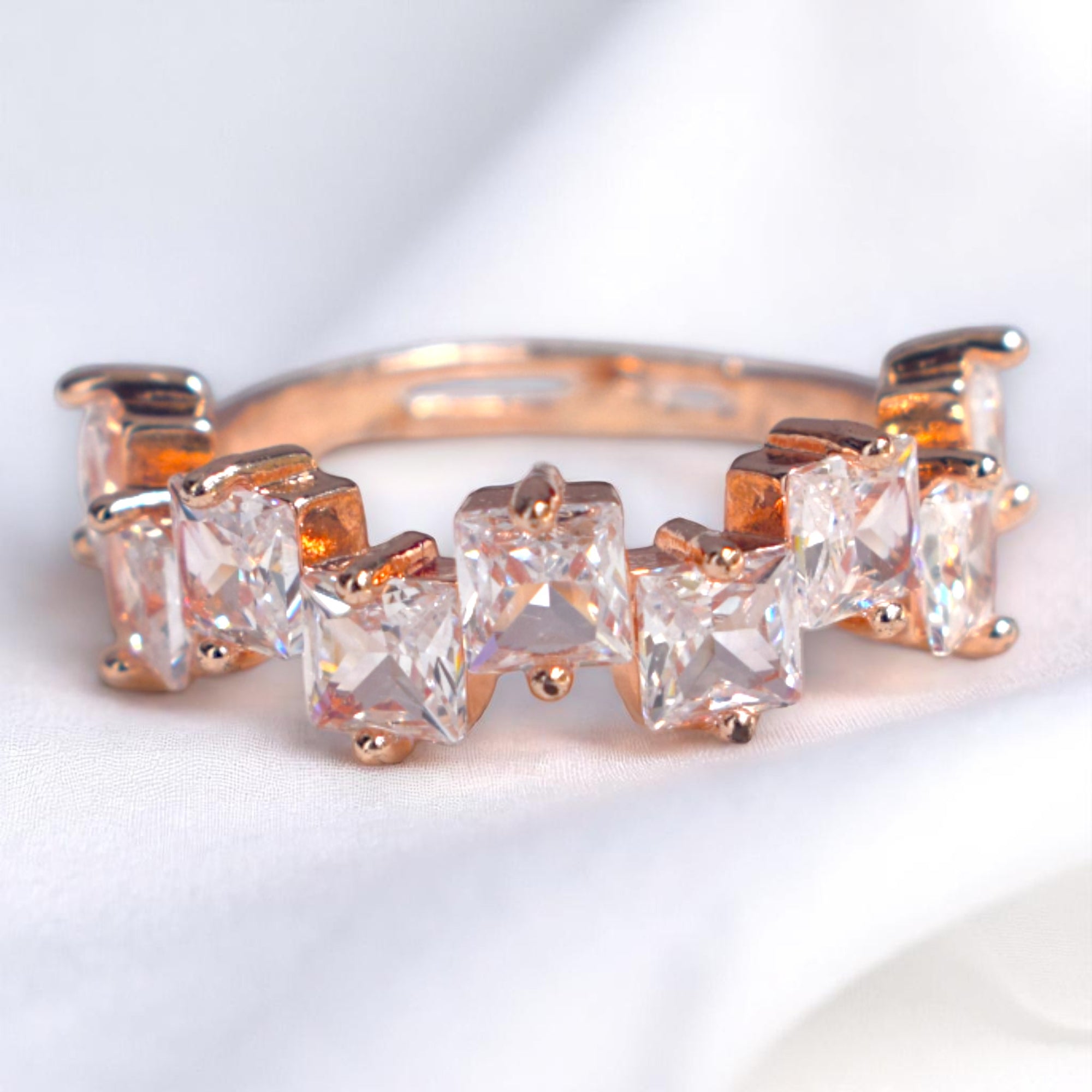 Rose gold ring with clear gemstones on a light background