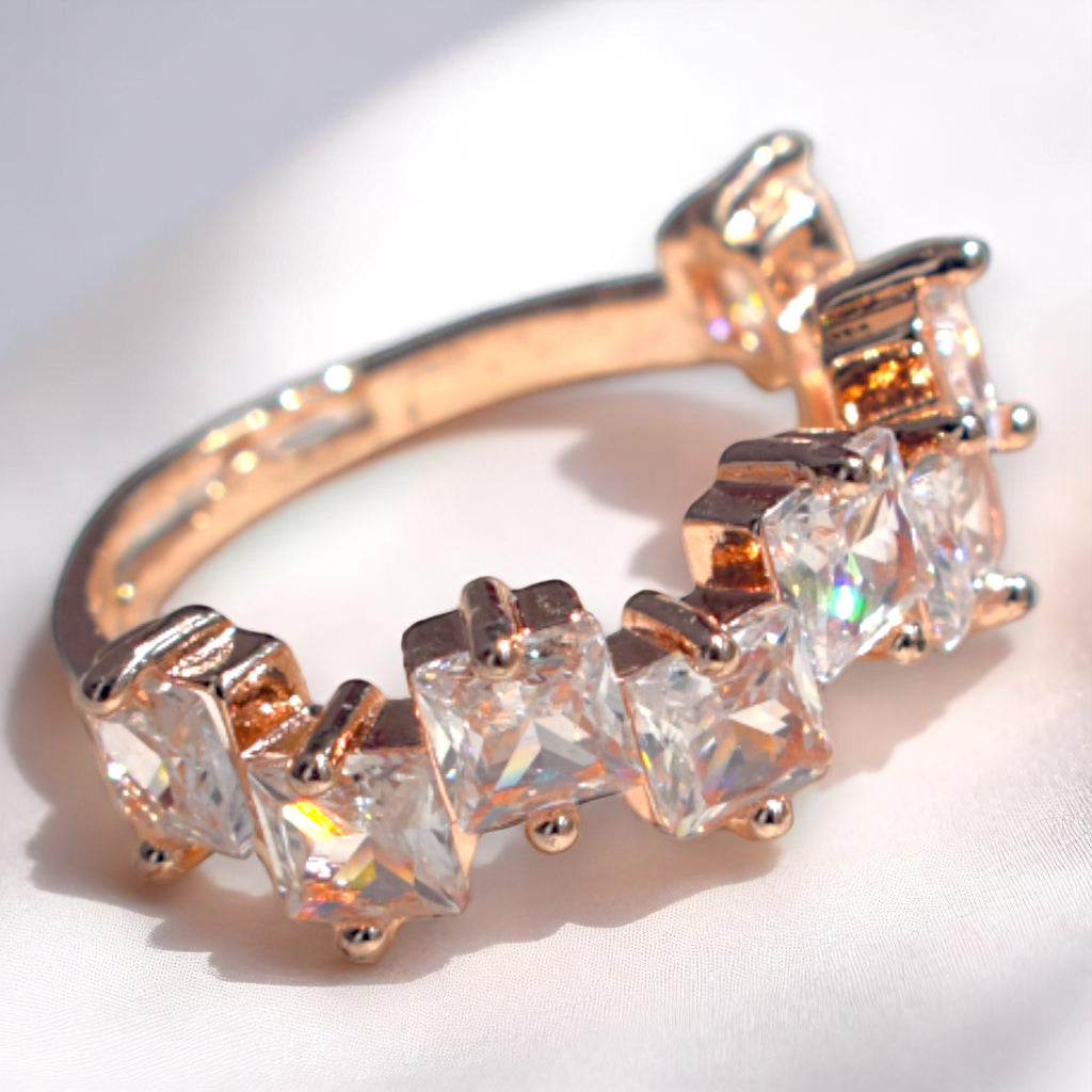 Rose gold ring with clear gemstones on a white background