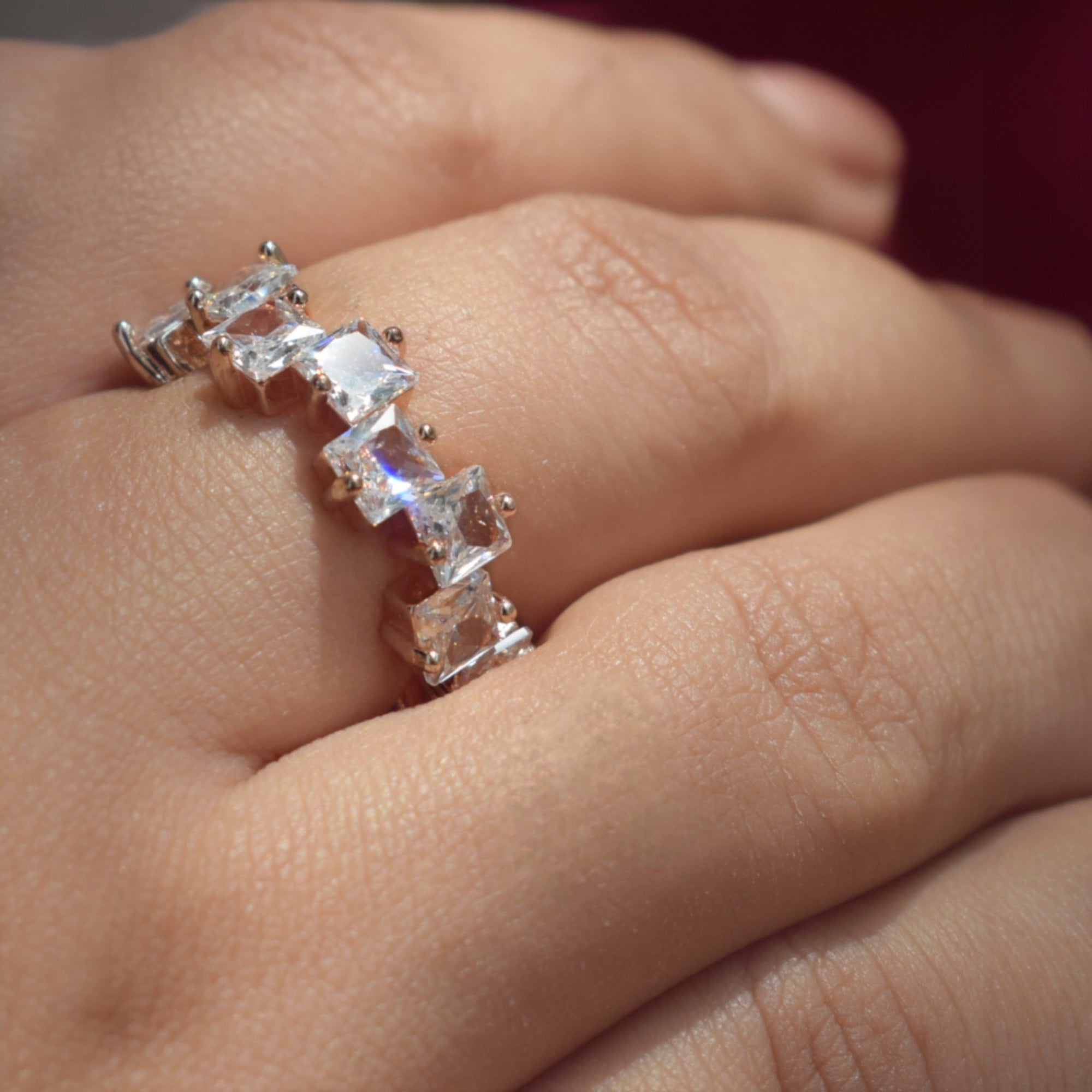 Rose gold ring with clear stones on a person's finger