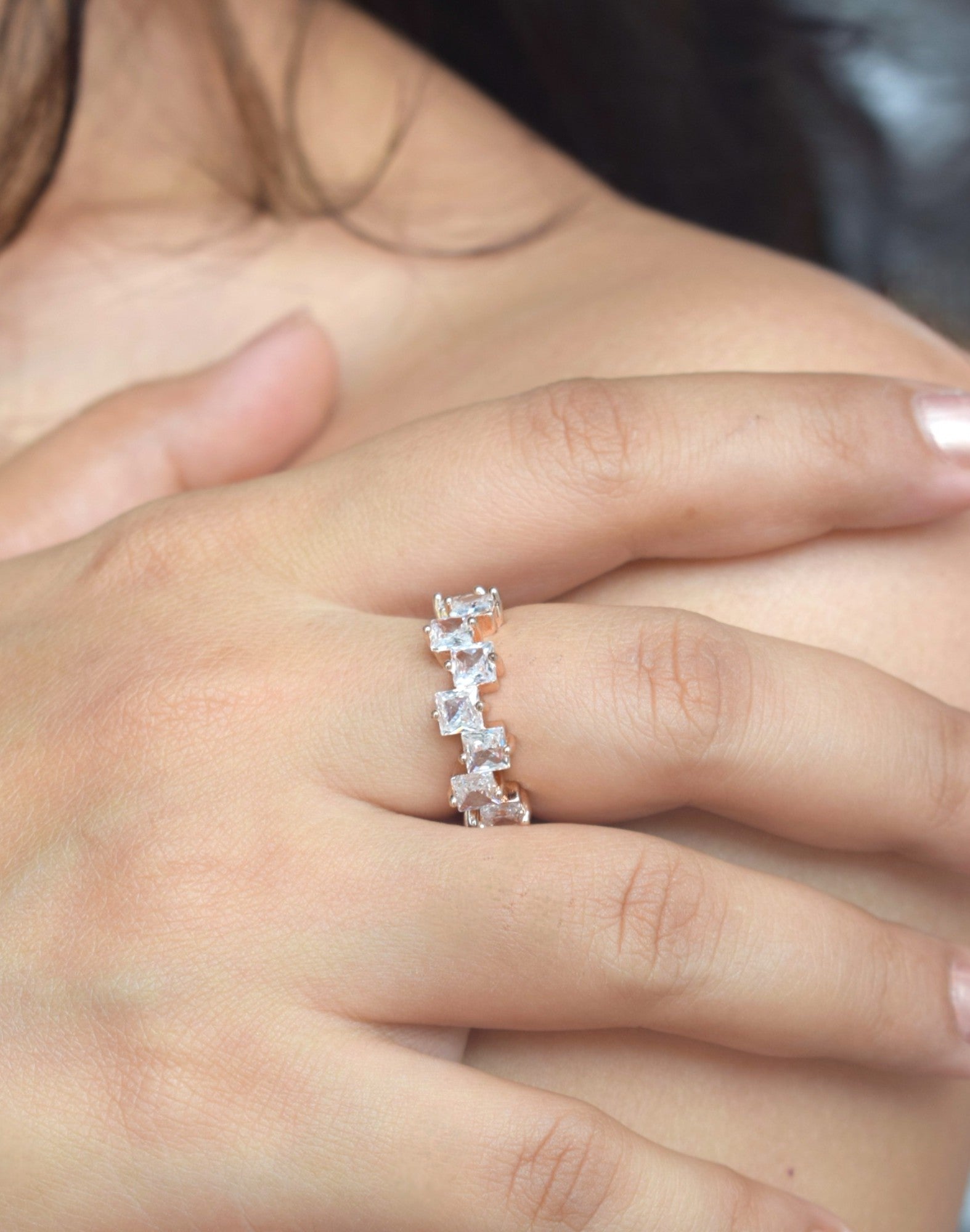 Rose gold ring with small diamonds on a person's finger
