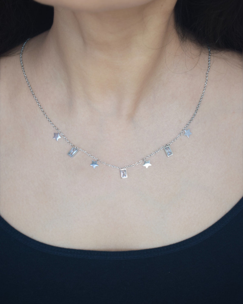 Necklace with small rectangular pendants on a person wearing a black top.