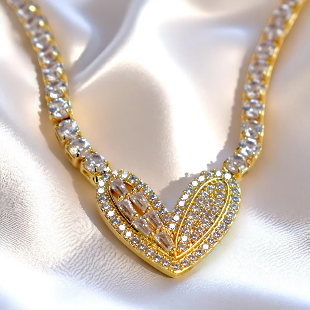 Gold necklace with heart-shaped pendant on a white fabric background