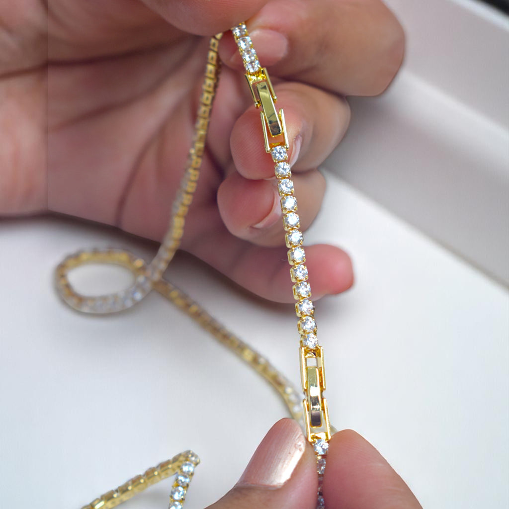 Gold chain with diamond-like stones held by a hand on a white background