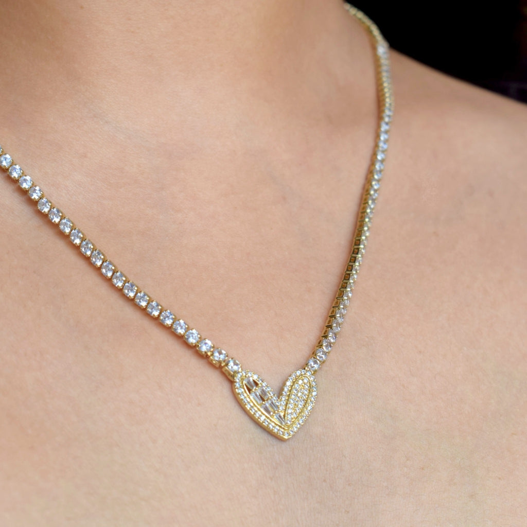 Gold necklace with a heart-shaped pendant on a person's neck