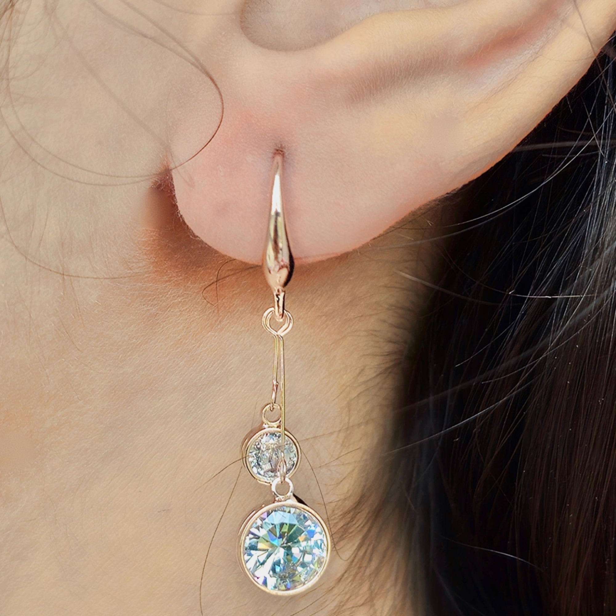 close up of kansobi single rose gold drop earrings with round zirconia diamonds worn by a girl