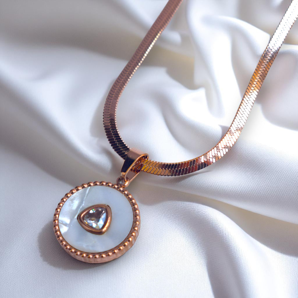 Rose gold necklace with a pendant on a white fabric background