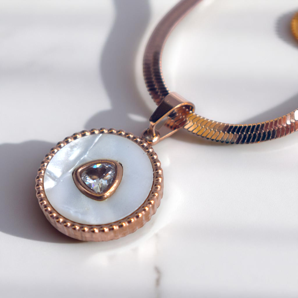 Rose gold necklace with a pendant featuring a heart-shaped gemstone on a white background