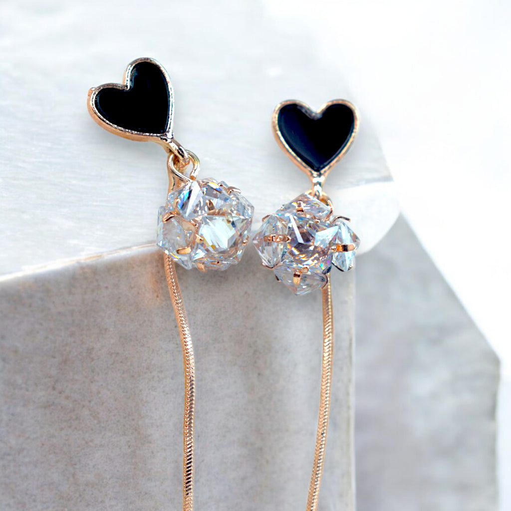 Close up of a Rose gold heart earrings with Round zirconia diamonds on a white marble floor