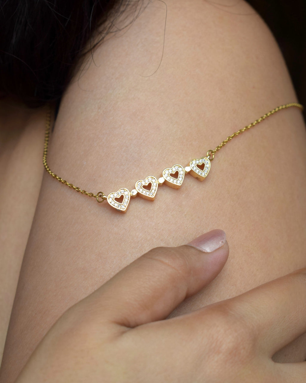 Gold anklet with heart-shaped charms on a person's ankle