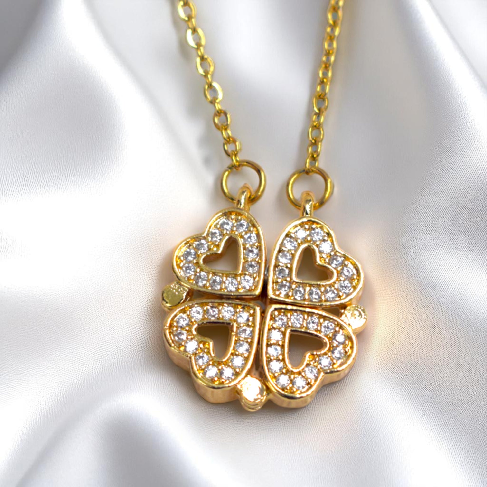 Gold necklace with a heart-shaped pendant on a white satin background