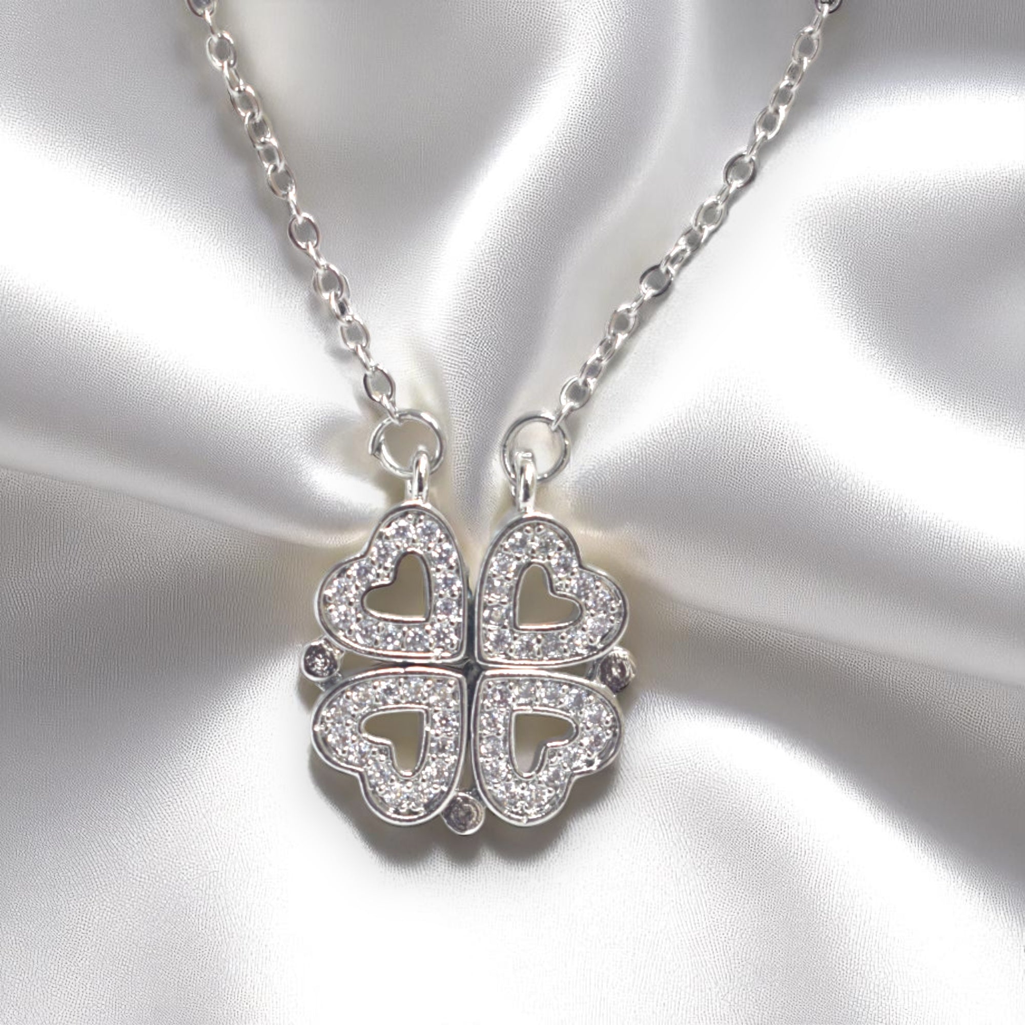 Silver necklace with a clover-shaped pendant on a satin background
