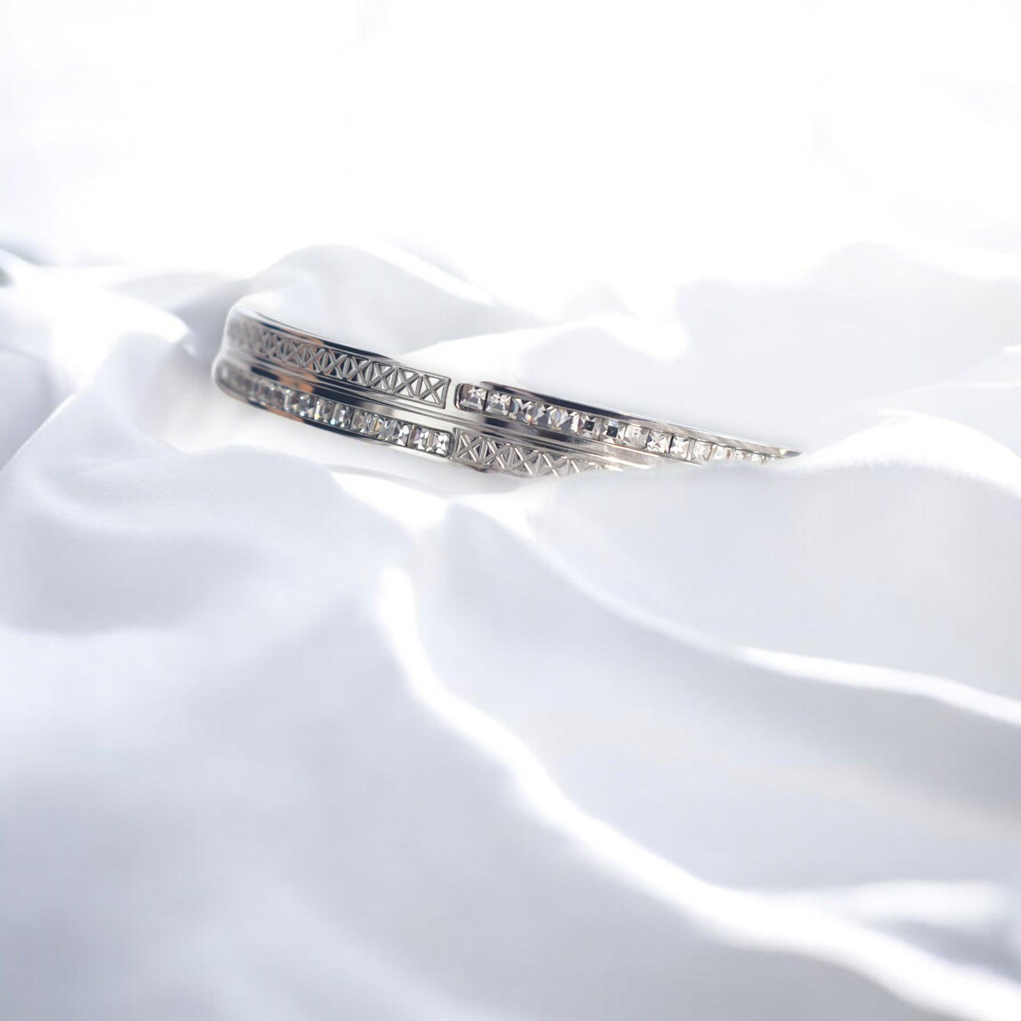 Diamond studded silver bangle on a white satin cloth