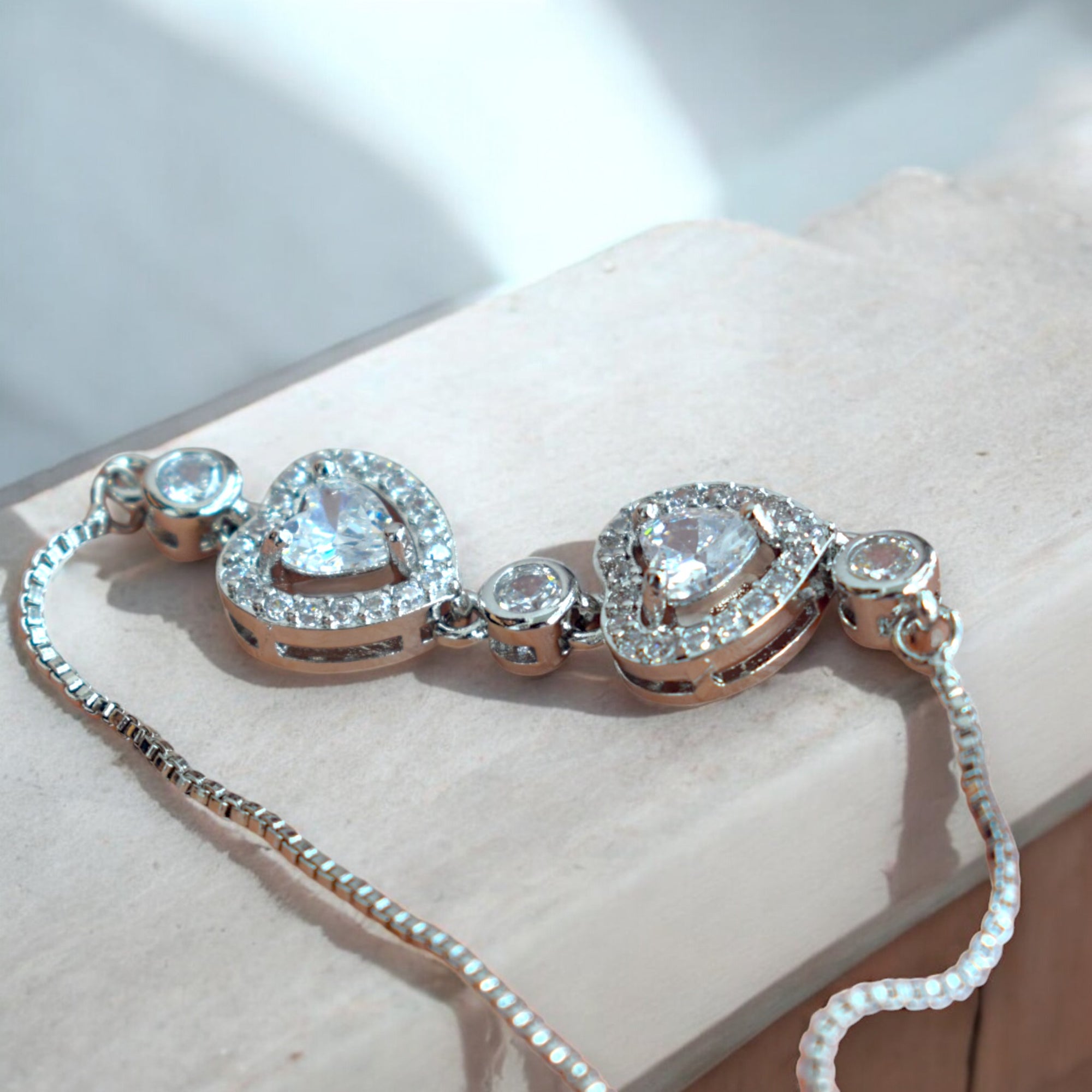 silver heart shaped diamond chain bracelet on a wooden surface
