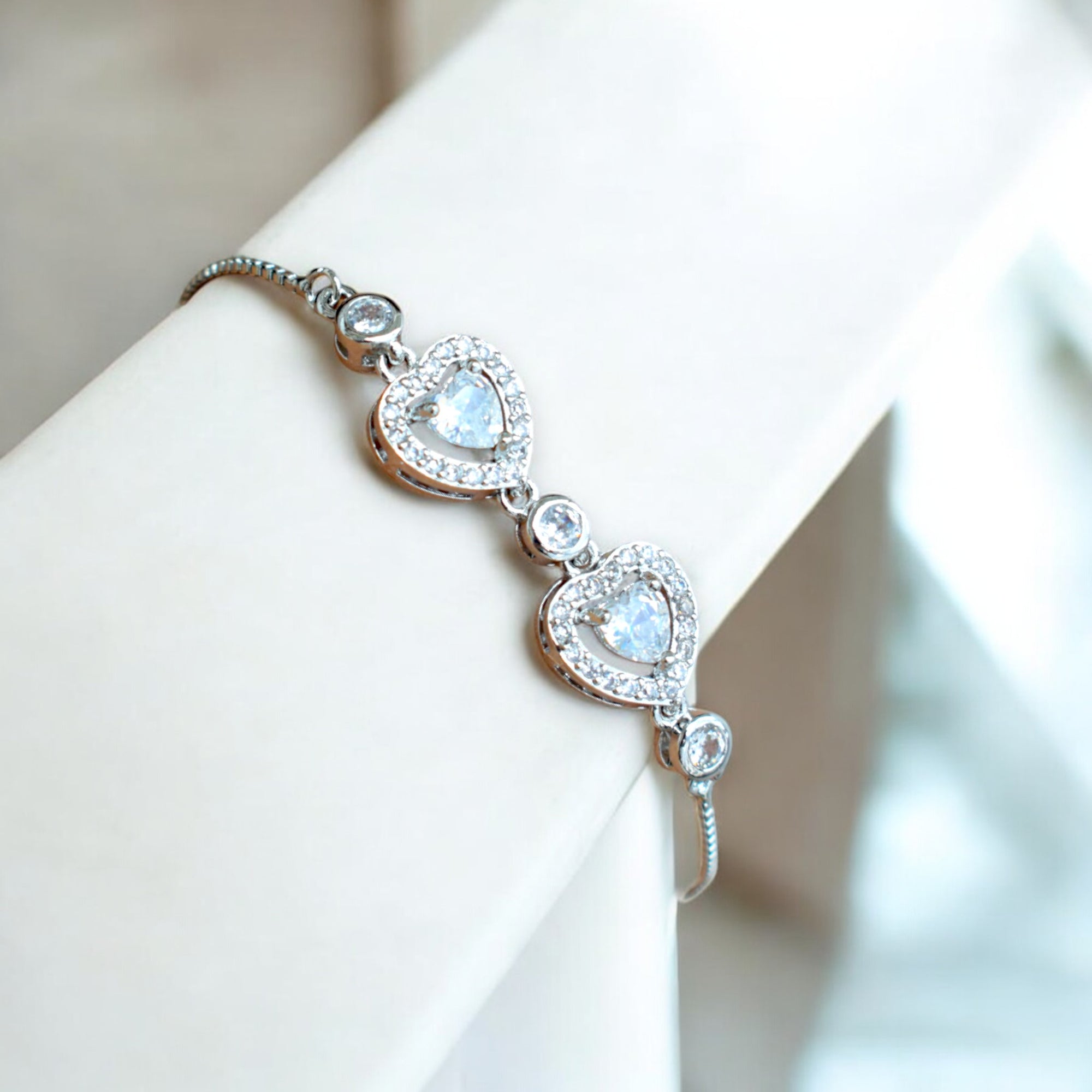 silver heart shaped diamond chain bracelet on a white stand