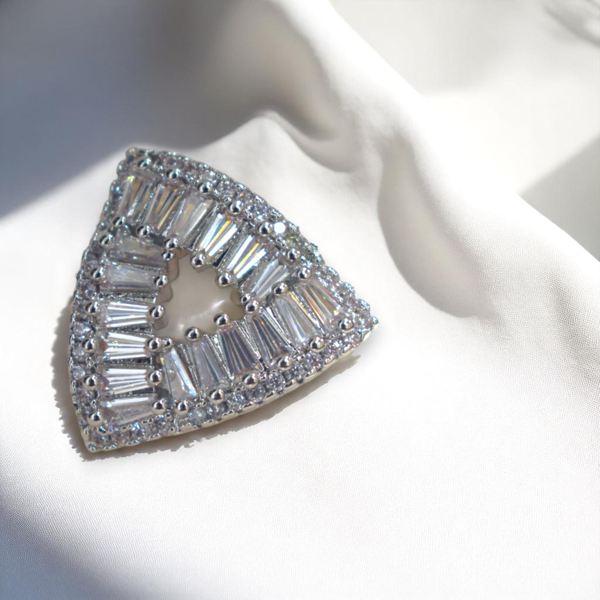 Triangular diamond ring with baguette cut stones on a white fabric background