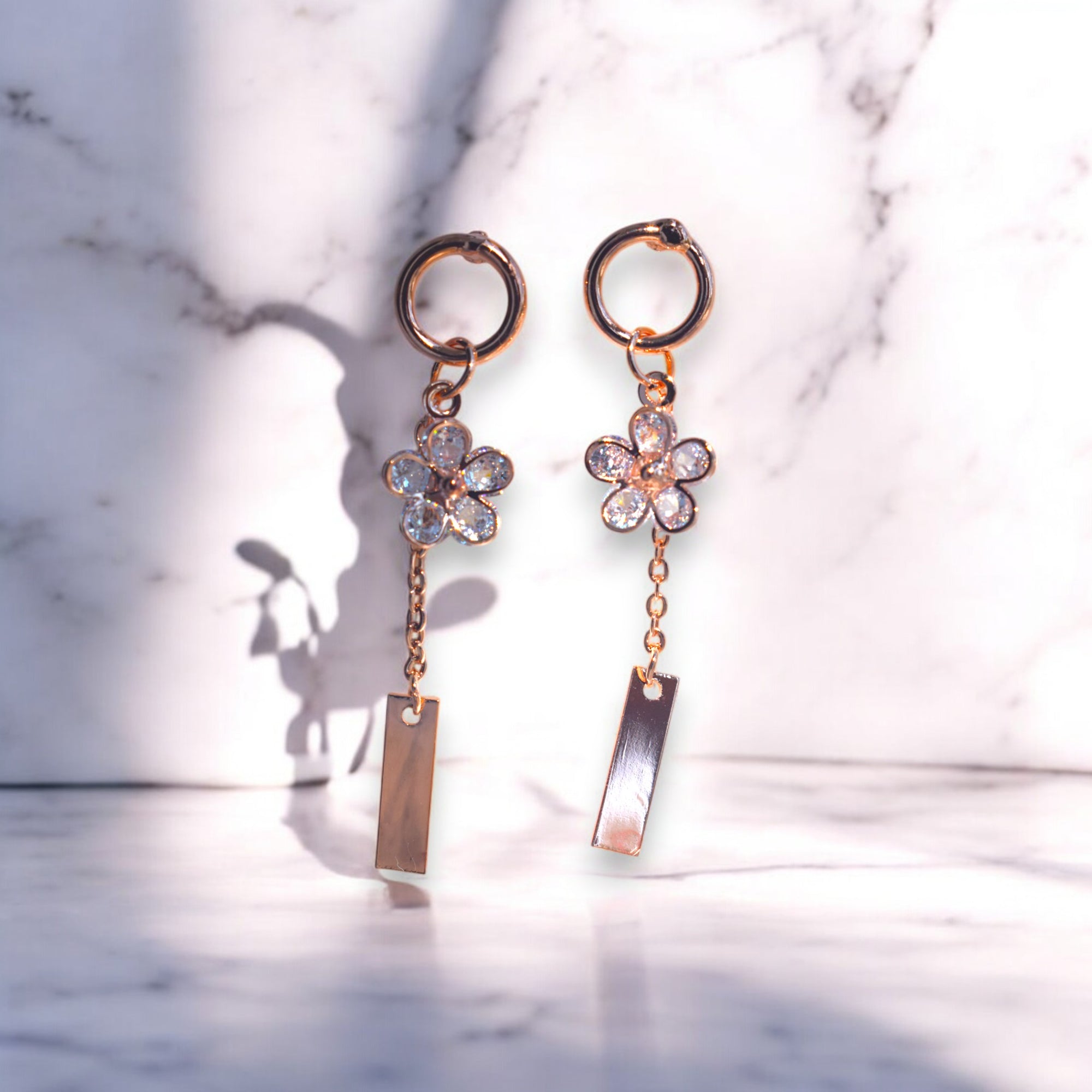 rose gold flower drip zirconia stone earrings on a white marble floor