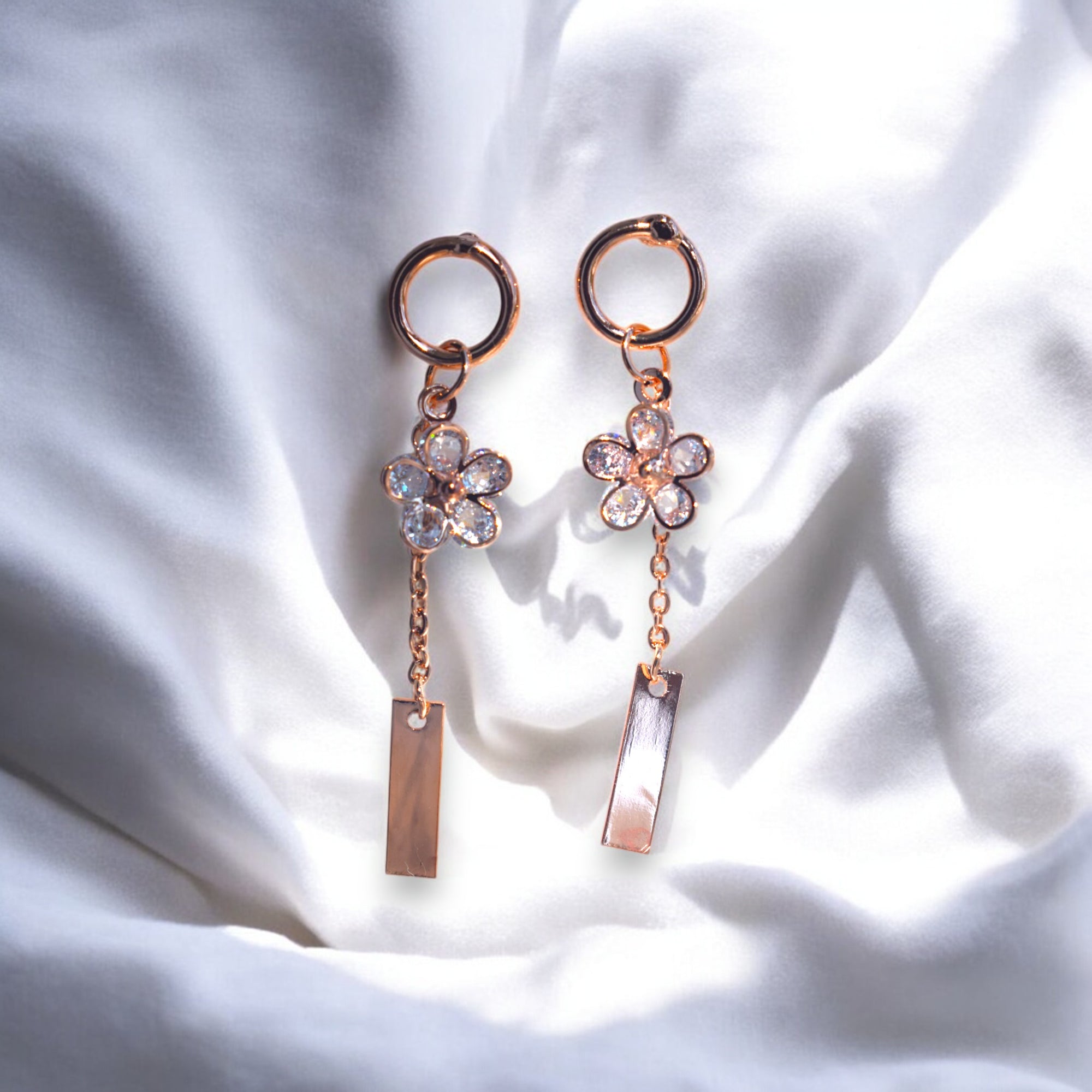 rose gold flower drip zirconia stone earrings on a white satin cloth