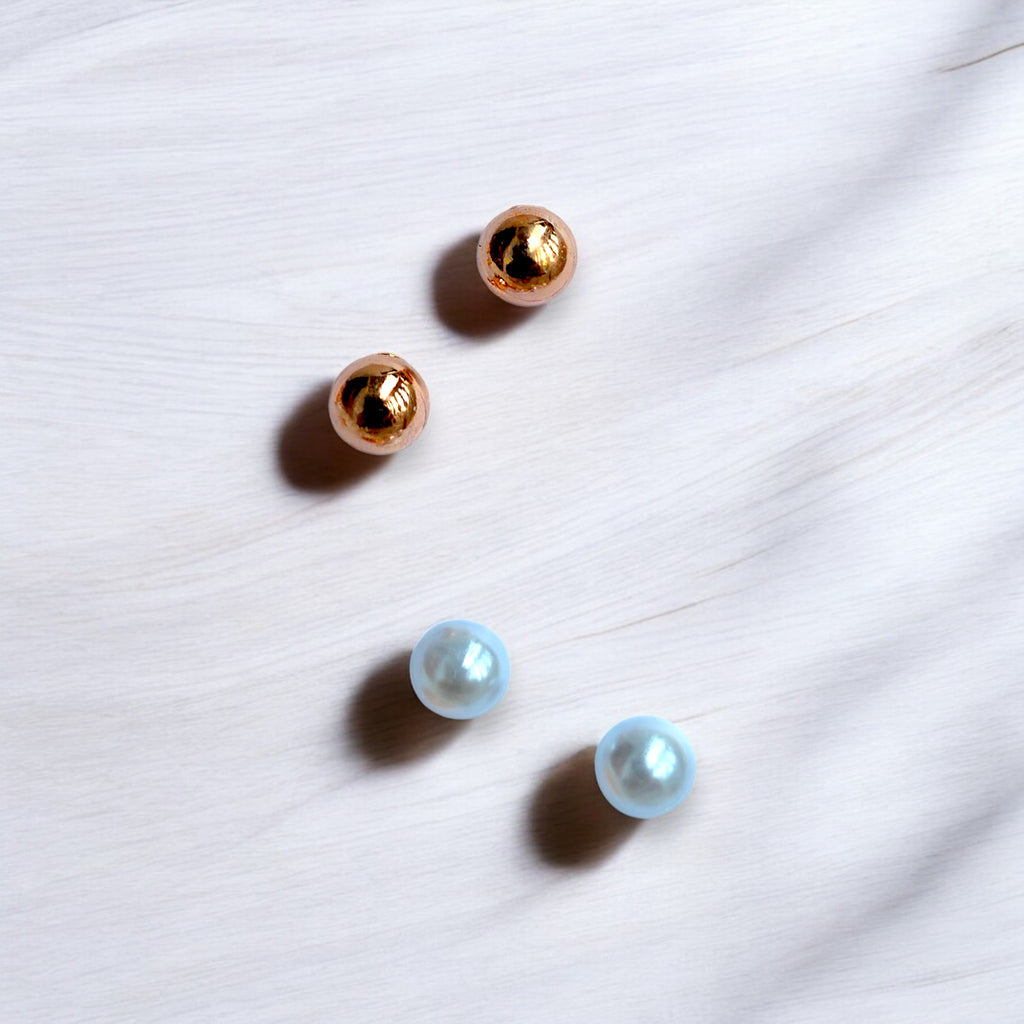 Rose Gold and Silver pearl studs on a white wooden floor