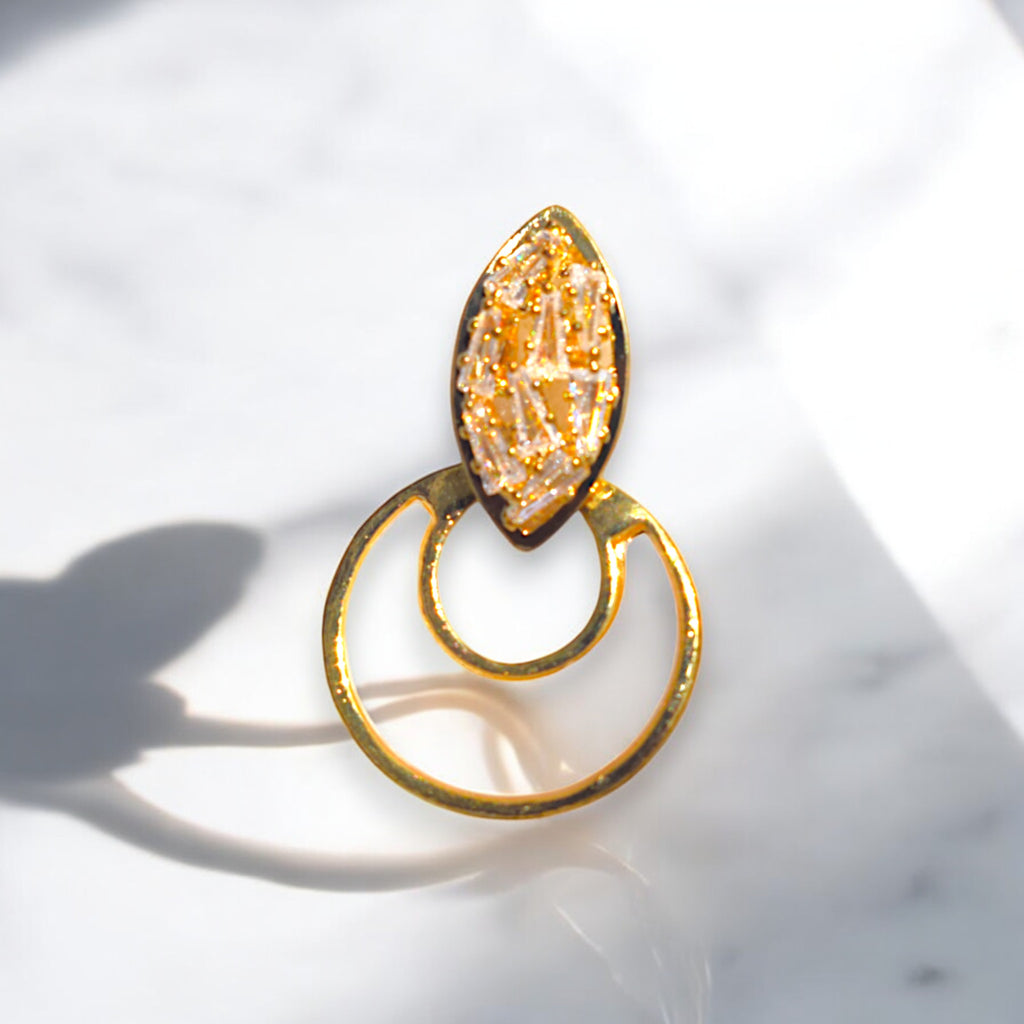 a single golden crescent moon zirconia stone studded earring on a white marble floor