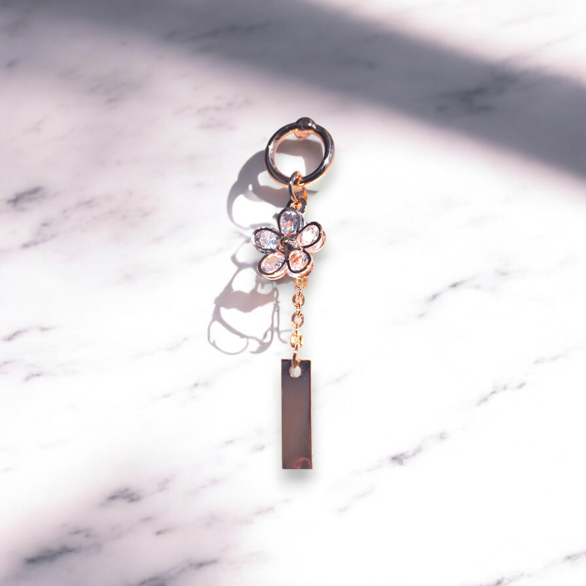 single rose gold flower drip zirconia stone earrings on a white marble floor